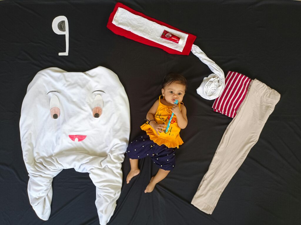 Adorable baby lying with a tooth-themed setup, depicting dental care.